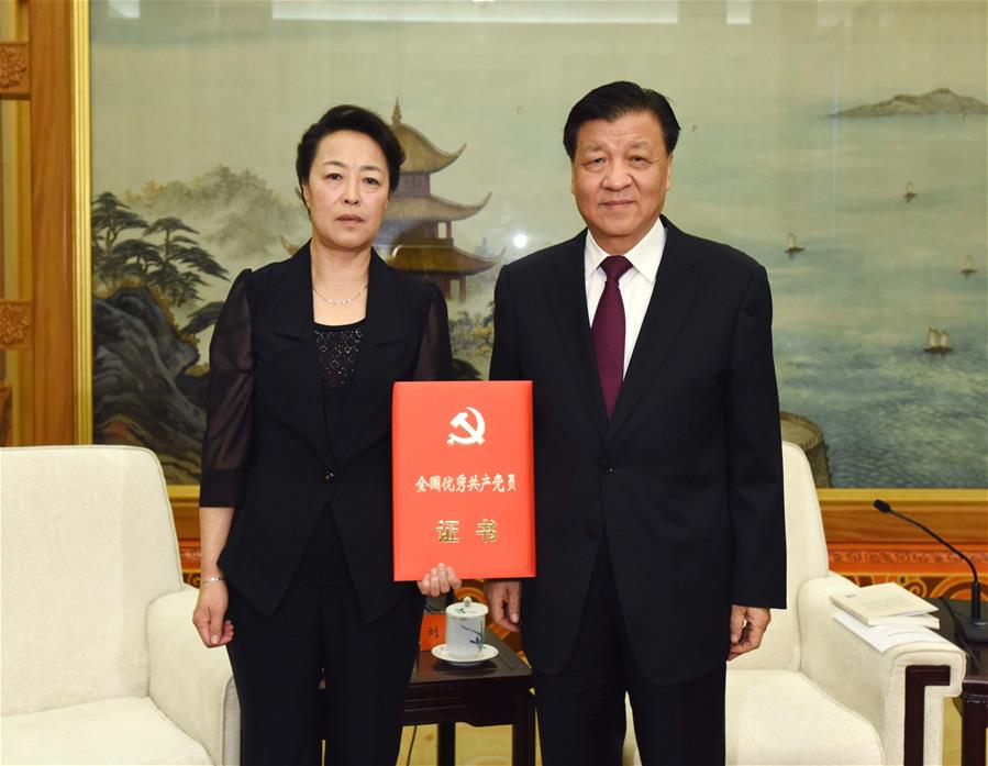 Liu Yunshan (R), a member of the Standing Committee of the Political Bureau of the Communist Party of China (CPC) Central Committee and secretary of the Secretariat of the CPC Central Committee, presents Li Baoguo