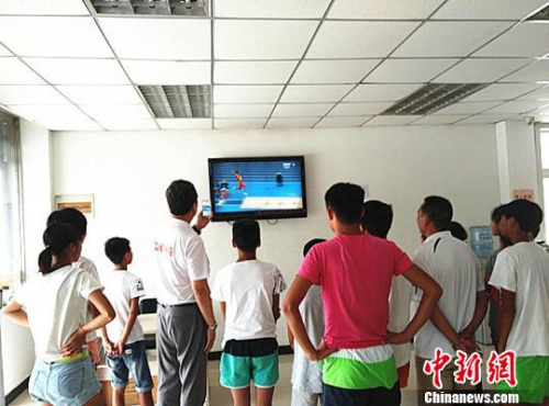 王志英以及徐州田径队的小队员们聚在电视前观看比