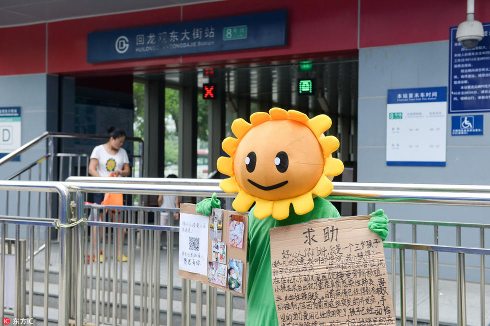 2016年8月13日，为了给患有噬血细胞综合征的4岁儿子一凡筹集医药费，广东河源的邹先生在北京街头穿着《植物大战僵尸》中向日葵的服装，5元一张求与路人合影。邹先生说，孩子在北京京都儿童医院做了造血干细胞移植后出现了肺部感染，前期已花了50多万，后续治疗费用还需要至少20万。图片来自（京华时报-东方IC）