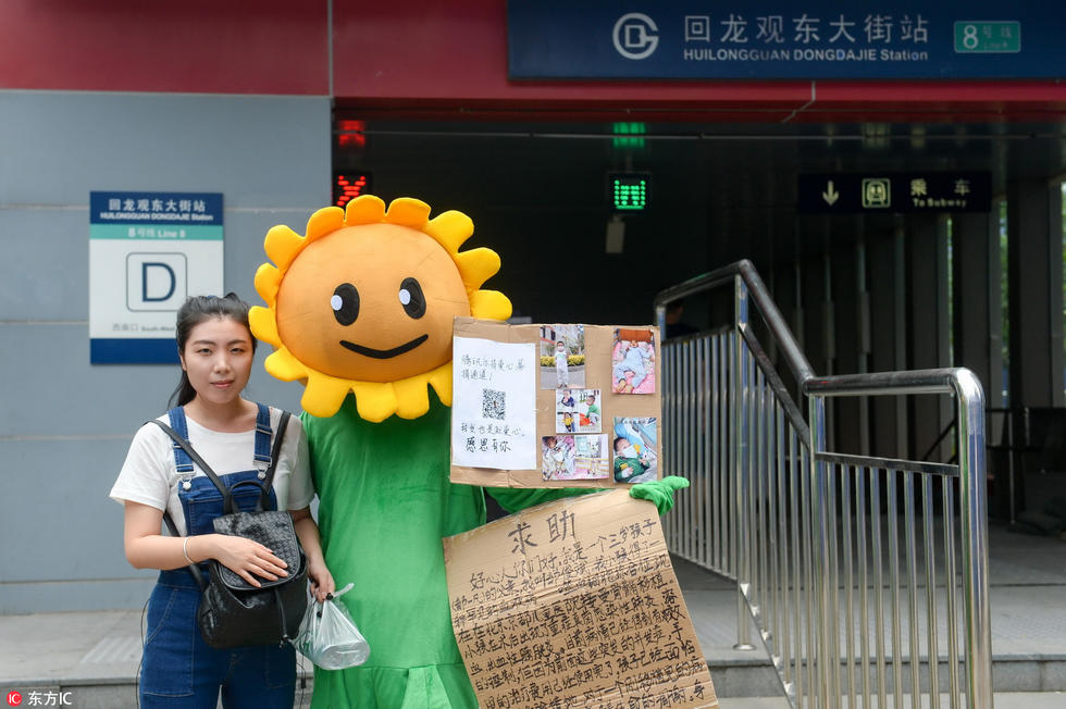 孩子父亲身穿向日葵装束在地铁站前合影凑药费。邹一凡3岁宝宝患家族性噬血细胞综合征，父亲变身向日葵求合影救子。邹先生说，孩子早产，取名“一凡”，寓意孩子此后的人生能一帆风顺，平凡快乐。去年11月，一凡持续高烧不退，服用多种退烧药都无效。今年3月，他带一凡来北京医院详细检查，确诊为家族性噬血细胞综合征。5月，一凡病情突然恶化，持续高烧不退，出现肝脾肿大、血象下降等问题。今年7月，一凡在北京京都儿童医院进行了造血干细胞移植手术。  邹先生称，一凡手术后出现了重症真菌性肺炎，常用药无法治疗，只能通过特殊渠道买昂贵的进口药治疗。目前给孩子治病已经花费50多万，欠下了30万元的债务。