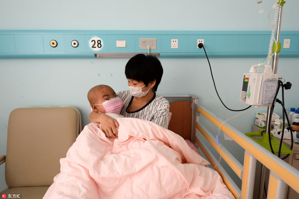 他戴着口罩躺在母亲的怀里，正在玩最喜欢的《植物大战僵尸》游戏。因服用药物较多，脸部显得比同龄孩子肿大。为了给孩子筹集医疗费，邹先生买来儿子最喜欢的植物大战僵尸造型的卡通服装，在烈日下手举牌子站在地铁门口求合影，一张5元钱。“虽然有些不好意思，穿着向日葵的厚衣服、戴着头饰也非常闷热，但是为了孩子，再多的苦我也愿意吃。”邹先生说。