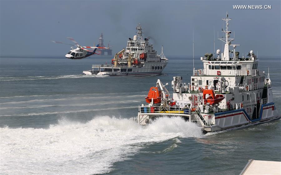 Rescue vessels and a helicopter take part in an emergency rescue drill held at the sea area near Fenghuang island in Sanya, south China