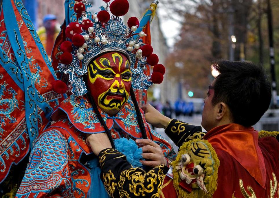 A dancer with the Chengdu (China) Panda float is assisted by a fellow dancer before the start of the Macy