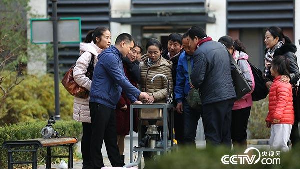 厨房发明达人杨明铮正在和小区的居民讲解自己厨余垃圾处理器的处理