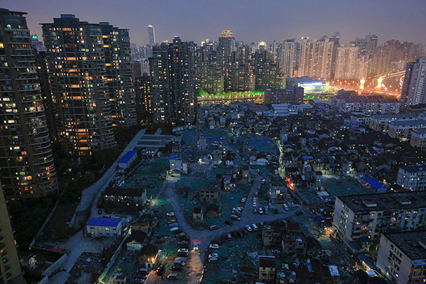 A night view of the old houses surrounded by new apartment buildings at Guangfuli neighbourhood in Shanghai, April 10, 2016. 