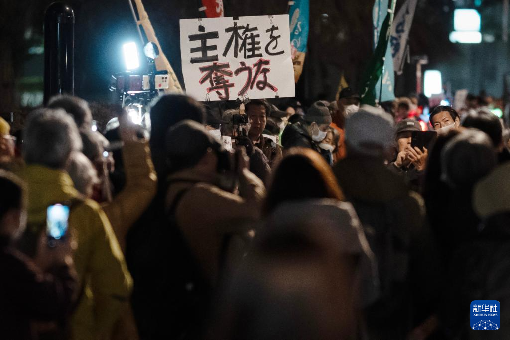 2月24日,在日本东京的众议院第二议员会馆前,民众手持标语参加抗议活动。新华社记者 贾浩成 摄