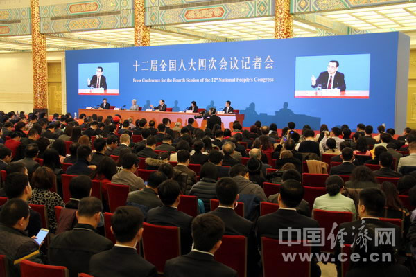 主席台背景墙上嵌入了两块大屏幕,播放总理答问的特写镜头.