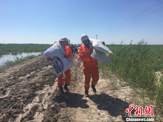 图为沙湾县消防人员正在扛着编织袋进行堵水救援. 张业臻 摄