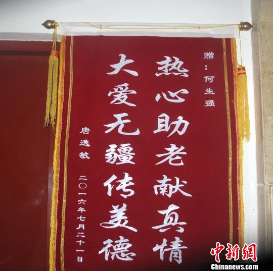 唐逸敏侄女赠送的锦旗挂在社区走廊的墙壁上. 杨东 摄