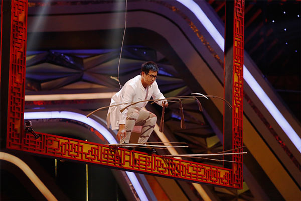 图:"平衡大师"韩遂宁站在被吊起4米的画框内平衡羽毛,稍有微小的晃动