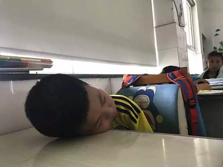 不过有一个身穿黄色球服的小男孩睁着大大的眼睛,显得有点无措,坐在他