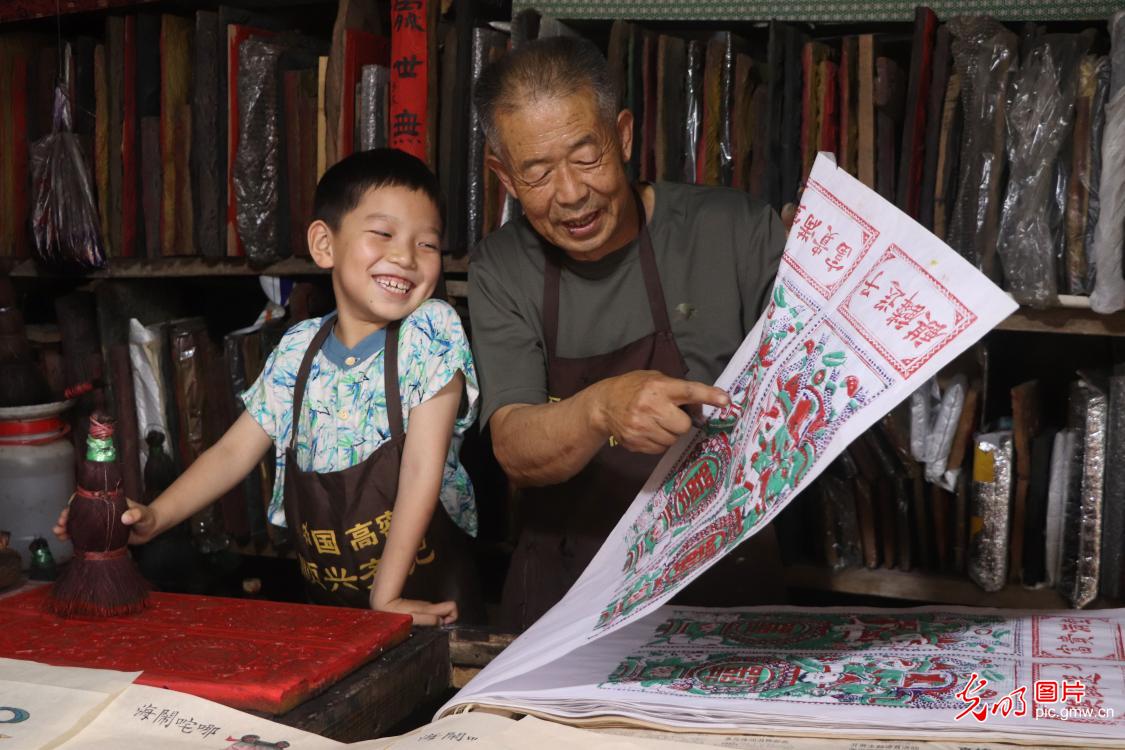 2025年6月14日,在山东省高密市夏庄镇朱家村,版画艺术家非遗传承人齐传新在工作室指导小朋友体验印制木版年画。高密木版年画,历史悠久,有着鲜明的地域传统文化特色和艺术感染力。(李海涛摄/光明图片)