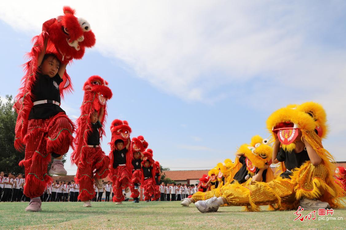 山东省滨州市博兴县店子镇第二小学组织舞狮社团的小学生向同学们表演舞狮,共同感受传统舞狮文化魅力。图为舞狮社团的小学生在向同学们表演舞狮。(陈彬摄/光明图片)