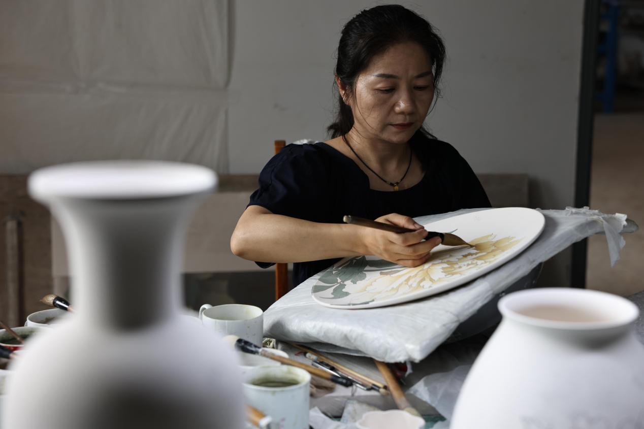 非遺匠人正在用釉下彩瓷汾水工藝給瓷盤上色（閔孝添/攝）
