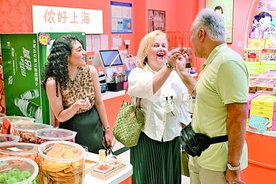 外国游客在上海南京路步行街的一家礼品店内品尝特色食品。 新华社发