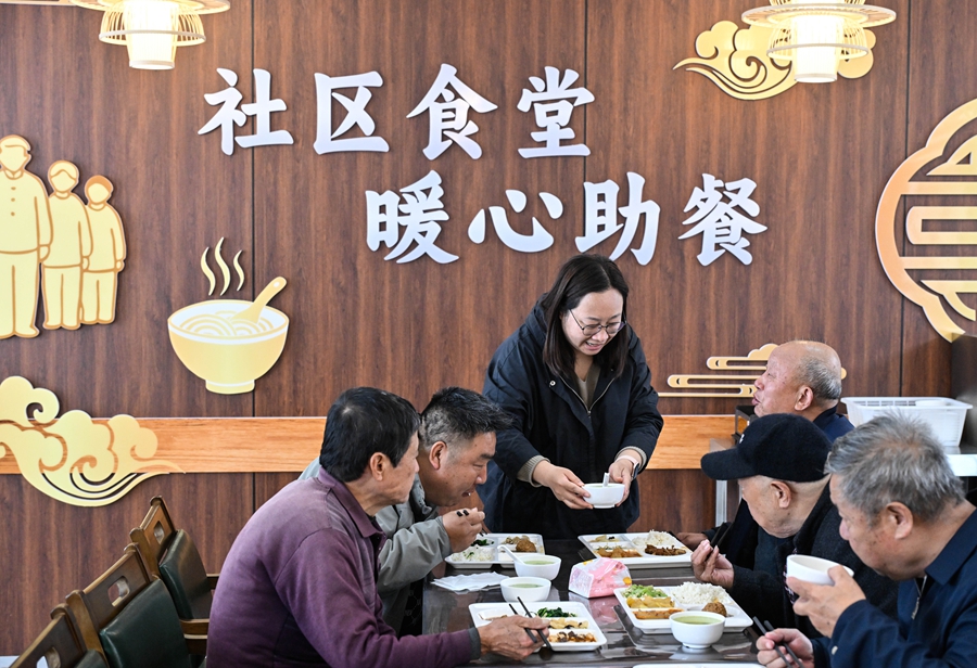 在江苏省扬州市江都区邵伯镇甘棠社区幸福邻里食堂，社区工作人员（左三）给老年居民端汤（2026年4月29日摄）。